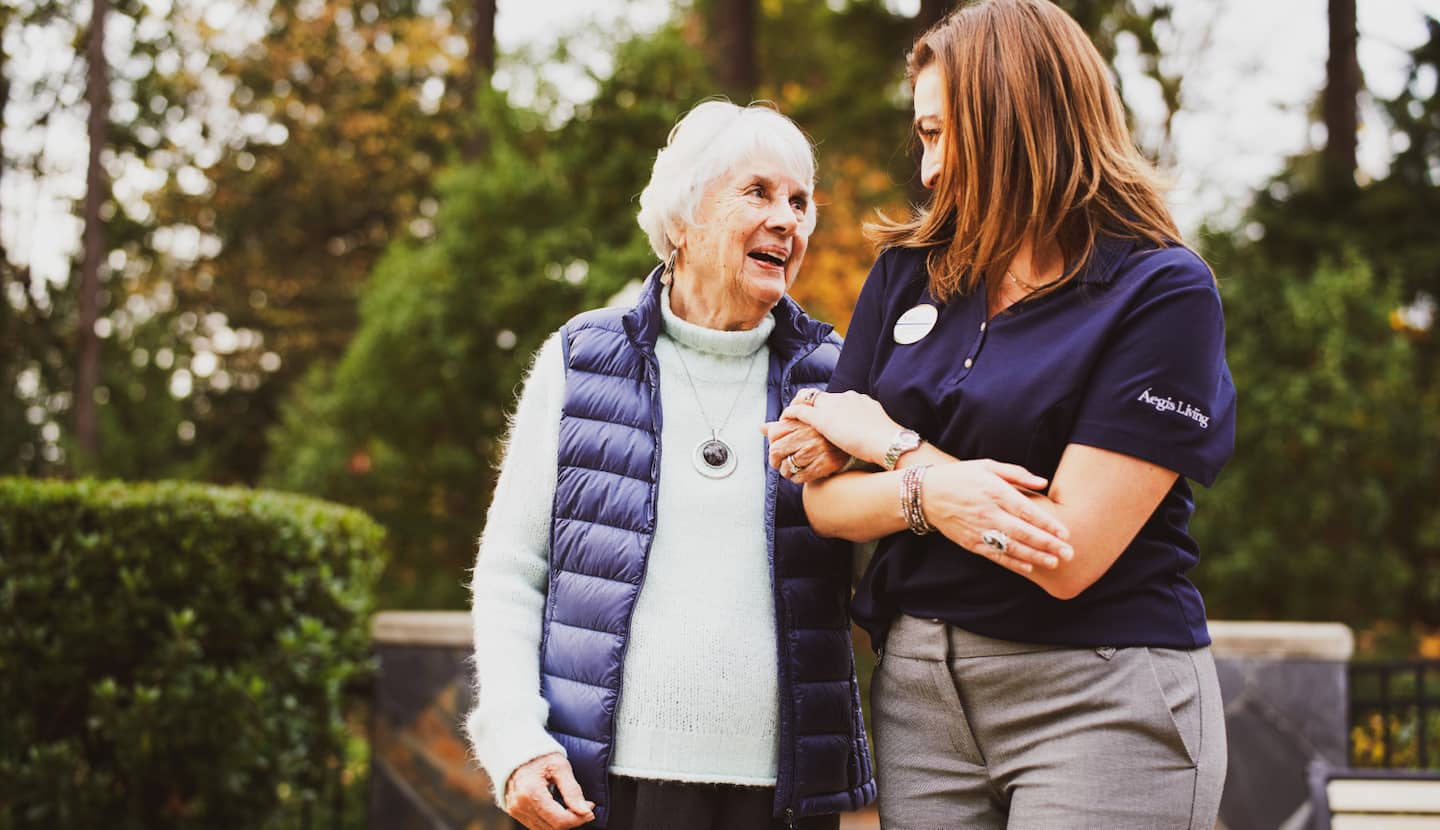 A resident smiling and walking with an employee