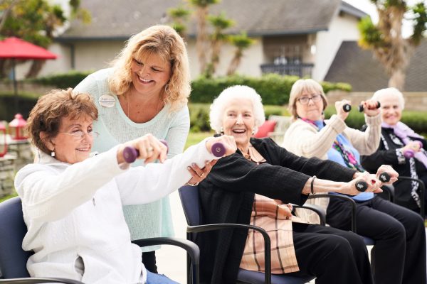 Residents sitting in chairs and exercising with weights