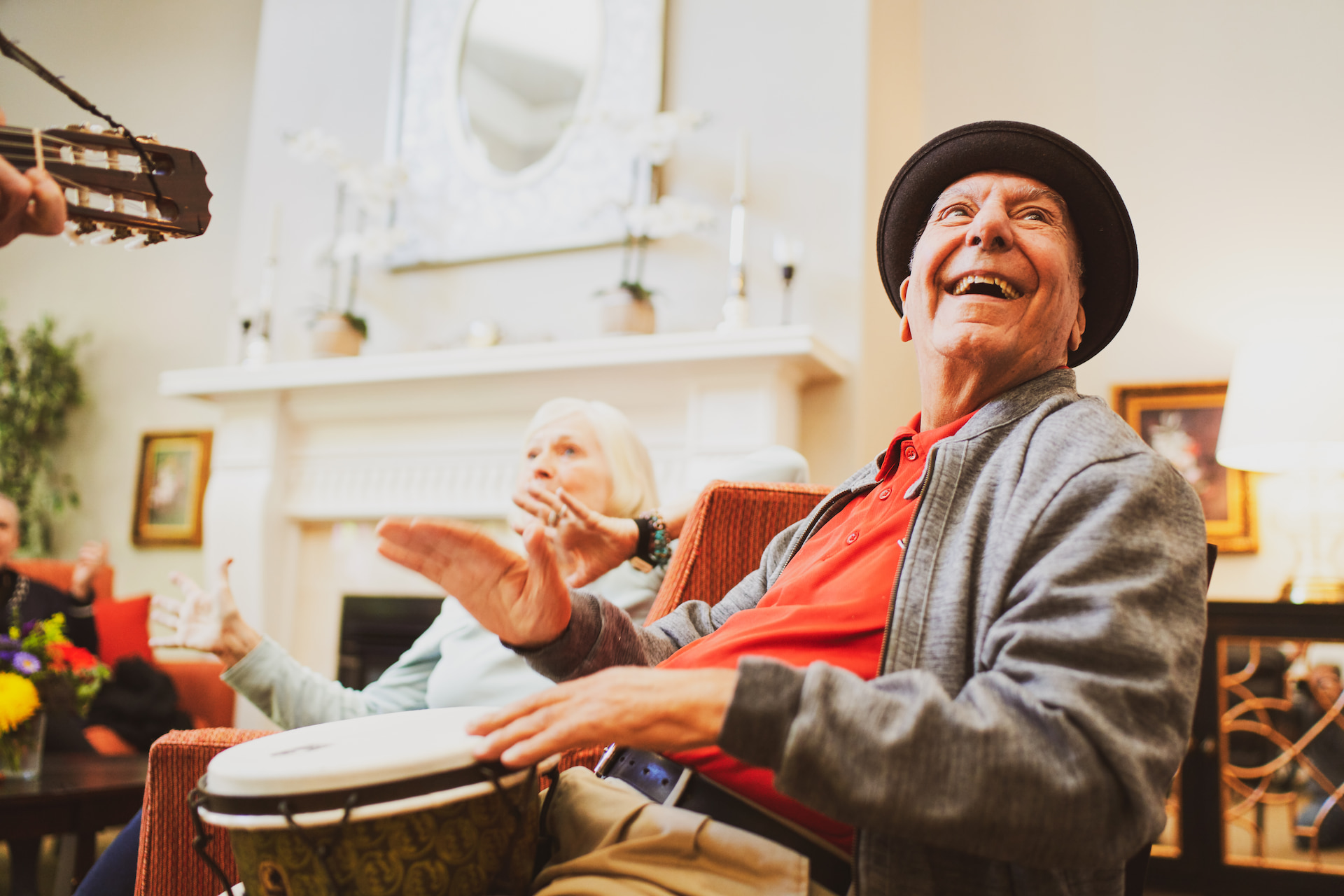 Two residents smiling and playing the bongos