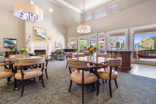 A seating area with lots of windows, tables, and chairs.