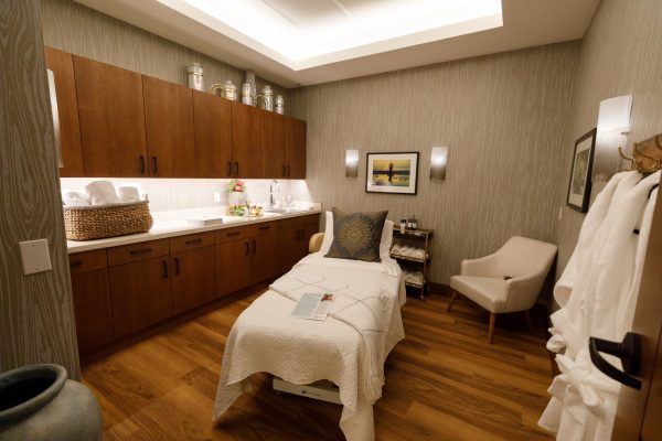 A massage room with a massage table and a chair in the corner