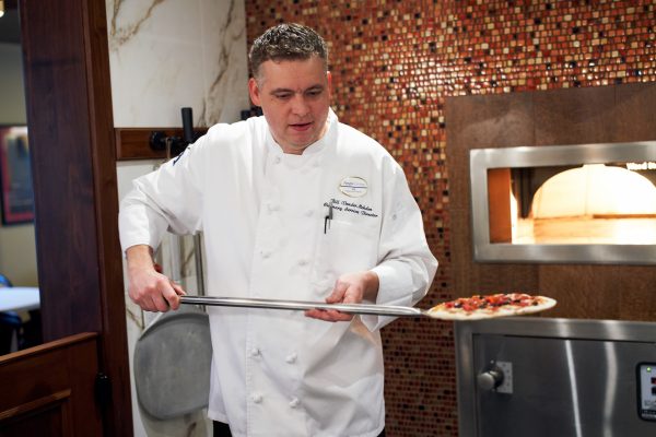 A chef pulling a pizza out of a pizza oven