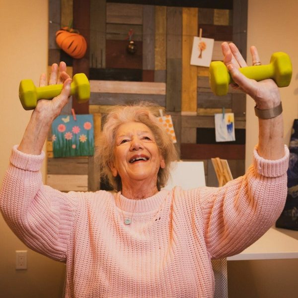 A resident smiling and lifting weights