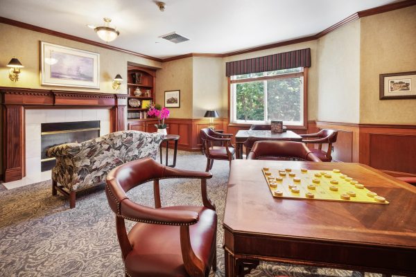 A seating area with a fireplace and tables and chairs for games.