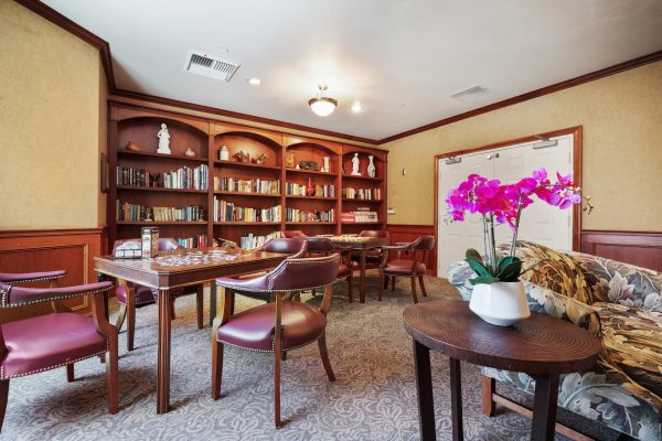 A recreation room with a small library and tables and chairs with games.