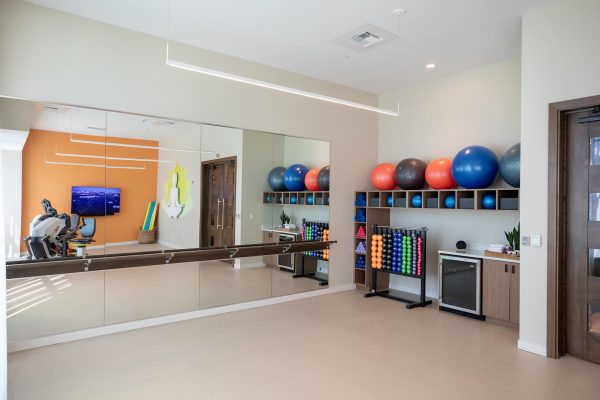 A workout room with a large mirror, balance balls, and weights.