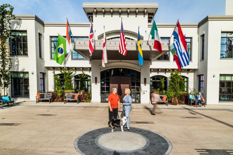 The main entrance of Aegis Living West Seattle, with two women and a dog standing out front