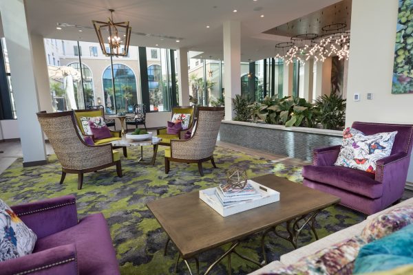 A seating area with a forest green carpet and purple velvet chairs.