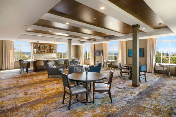 A large seating area with tables, chairs, and a bar area toward the back of the room.