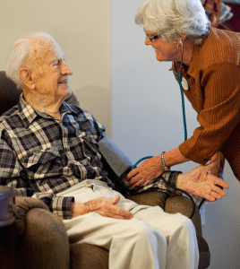 woman taking elderly man's blood pressure