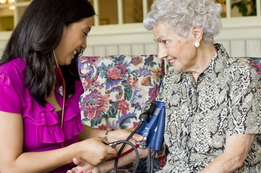 Aegis Living staff nurse measures resident's blood pressure