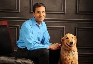 Dr. Rahul Khurana MD sits in chair accompanied by Golden Retriever