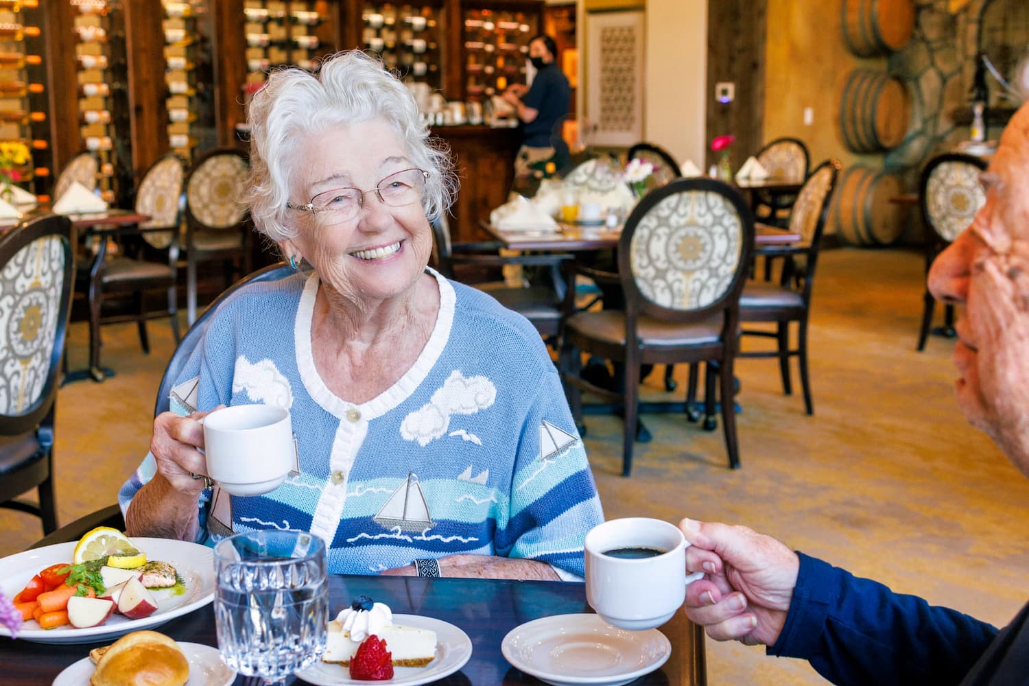 Two residents smiling, holding coffee at breakfast