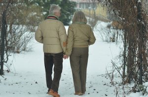 an elderly couple walking in the snow
