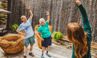 Two seniors stretching on outdoor patio at Aegis Living Mercer Island