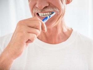 Elderly man brushing teeth.