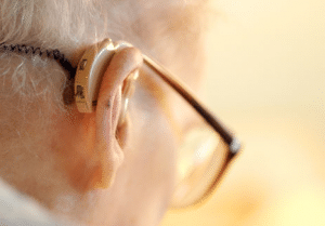 Closeup of elderly man's hearing aid behind his right ear