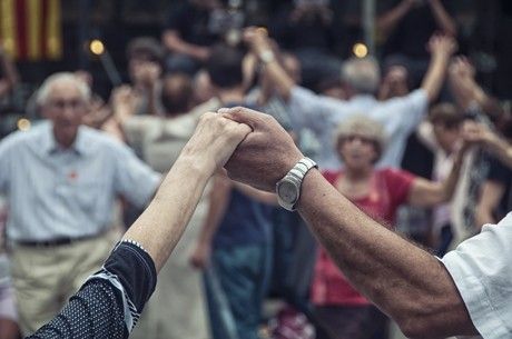 close up image of two elderly people holding hands while in a group activity