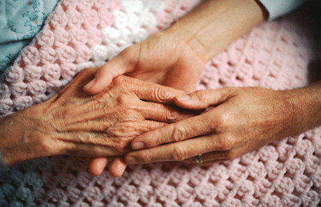 caregiver holding patients hands