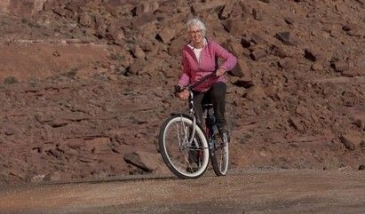 a senior woman biking on a trail.