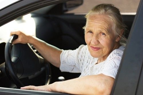 a senior woman on the driving side of a car looking out the window.