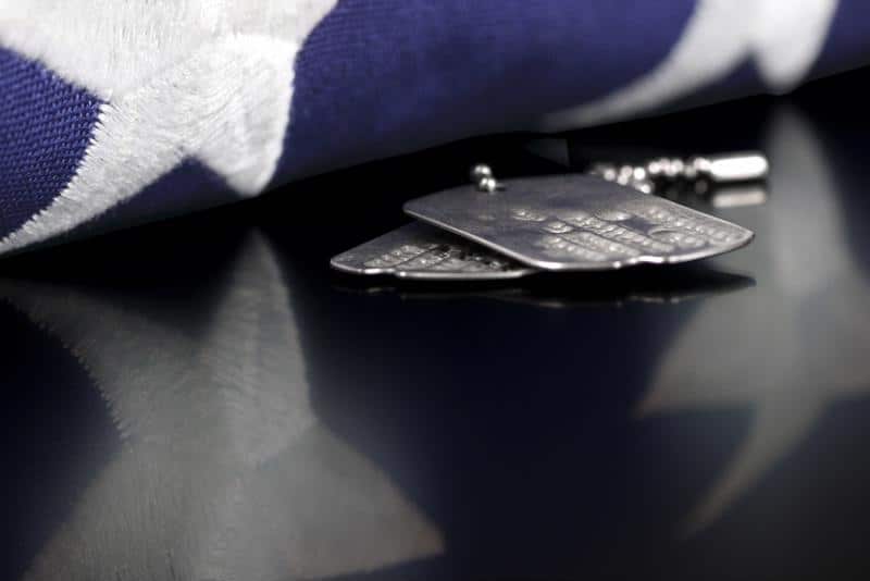 military dog tags set beside blue field of the American flag