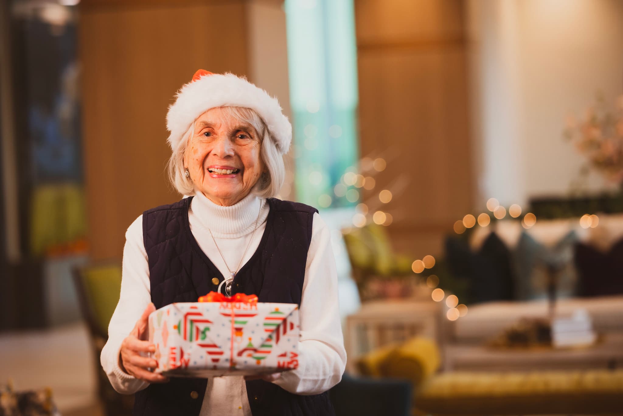 A resident wearing a Santa hat and holding a present