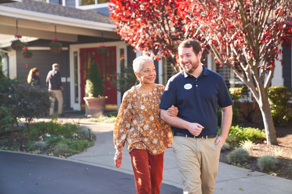 An employee walking arm in arm with a resident